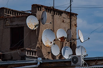 A bunch of satelite dishes hanged from a building