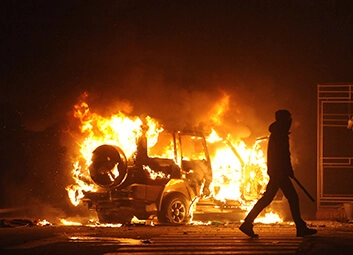 Burning Car, riot-looking man walking away from the scene